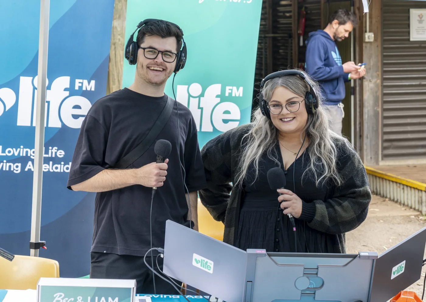 Life FM presenters wearing headsets at a branded community broadcast desk.